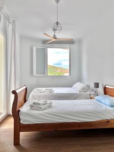 Ático con Vistas في فيليس-روبايو: سريرين في غرفة بيضاء مع نافذة