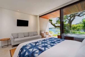 een slaapkamer met een bed, een bank en een raam bij Wyndham Ilhabela Casa Di Sirena in Ilhabela