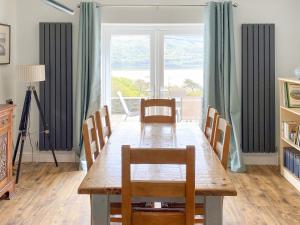 a dining room table with chairs and a large window at Cae-fadog Fach in Barmouth