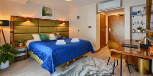 um quarto com uma grande cama azul e uma secretária em EDEN Rajskie Spa em Rajskie Sakowczyk