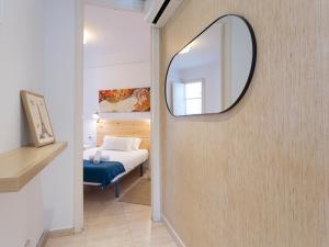 um quarto com uma cama e um espelho na parede em Centric Sagrada Familia Apartments em Barcelona