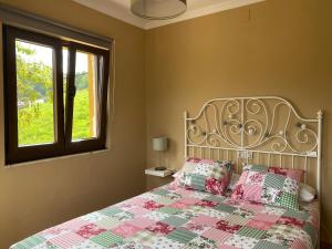 a bedroom with a bed with a quilt and a window at La Pedrosa in Fontanina