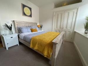 a bedroom with a bed with a yellow blanket on it at Luxurious 2 bedroom apartment in central Berwick in Berwick-Upon-Tweed