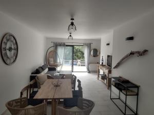 a living room with a table and chairs and a clock at villa bois flottés in Le Verdon-sur-Mer