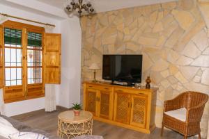a living room with a tv on a stone wall at La Tesela in Priego de Córdoba