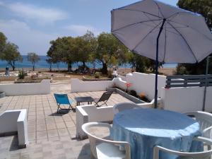 eine Terrasse mit einem Tisch, einem Sonnenschirm und Stühlen in der Unterkunft Endless BLUE Lahania in Lachania