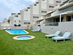 a yard with chairs and a swimming pool in front of a building at 204 Marbella Umhlanga in Durban