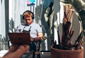 a man wearing headphones sitting in a chair with a laptop at Selina Boavista Ericeira in Ericeira