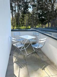 een tafel en 2 stoelen op een balkon bij Appartement Le Mans proche du circuit des 24h in Changé