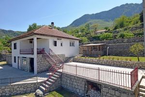 a white house with a stone retaining wall and stairs at Country House Vukmanovic Bukovik in Virpazar
