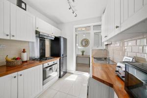a kitchen with white cabinets and wooden counter tops at Bright 2 Bed Perfect Central Hub in London
