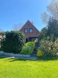 a brick house with bushes in front of a yard at Deichtraum - 1020 in Dahme