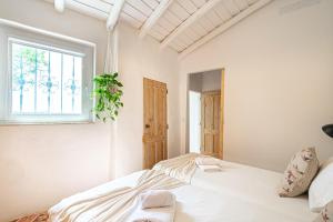 ein weißes Schlafzimmer mit einem Bett und einem Fenster in der Unterkunft BeGuest Casa Romãzeira Typical Vila in Alfarrobeira