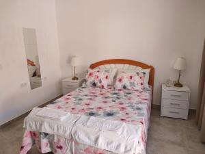 1 dormitorio con 1 cama con colcha de flores y 2 mesitas de noche en Casa Alba 2 en Puerto del Rosario