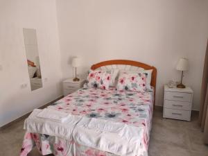 a bedroom with a bed with a floral bedspread and two night stands at Casa Alba 2 in Puerto del Rosario
