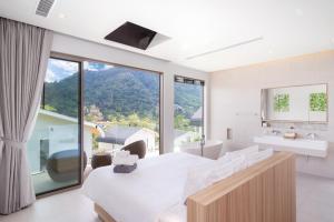a bedroom with a white bed and a large window at Himmapana Villas - Hills in Kamala Beach