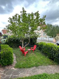 twee rode banken en een tafel onder een boom bij Villa Schmitt in Sélestat