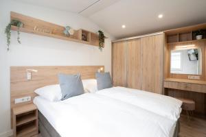 a bedroom with a large white bed and wooden walls at Ostseecamp Ferienhaus "Horizont" in Scharbeutz
