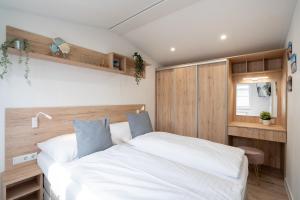 a bedroom with two white beds and wooden walls at Ostseecamp Ferienhaus "Koralle" in Scharbeutz