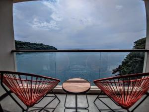 d'un balcon avec deux chaises et une table devant une fenêtre. dans l'établissement Louis Kienne Resort Senggigi, à Senggigi