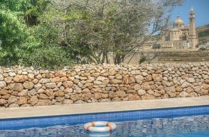 une piscine avec un mur de roche et un radeau dans l'eau dans l'établissement Dar il-Wied Farmhouse, à L-Għarb