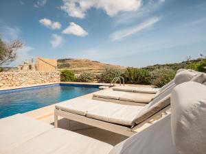 - une piscine avec deux chaises longues à côté de la piscine dans l'établissement Dar il-Wied Farmhouse, à L-Għarb