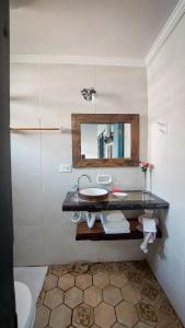 La salle de bains est pourvue d'un lavabo et d'un miroir. dans l'établissement Suítes em casa centenária no centro de Socorro, à Socorro