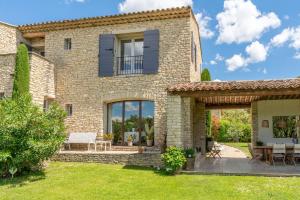 ein Steinhaus mit einer Terrasse und einem Hof in der Unterkunft Villa Les Terrasses de Gordes in Gordes