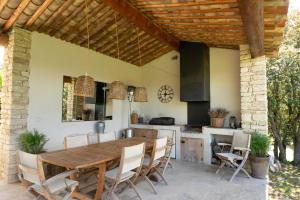 eine Außenküche mit einem Holztisch und Stühlen in der Unterkunft Villa Les Terrasses de Gordes in Gordes