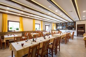 una sala da pranzo con tavoli, sedie e tende gialle di Gasthaus Panzió a Szilvásvárad