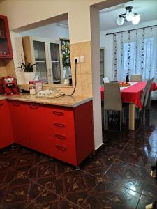a kitchen with red cabinets and a dining table at Casă de vacanță Lidia in Albac +11 photos