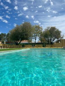 a large blue swimming pool with a wooden fence at Quinta da Boavista in Vila Nova de Milfontes