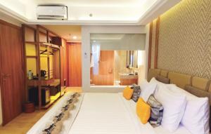 - une chambre avec un grand lit blanc et des oreillers jaunes dans l'établissement Louis Kienne Resort Senggigi, à Senggigi
