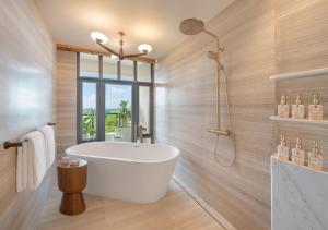 a bathroom with a white tub and a window at Centara Reserve Samui - SHA Plus in Chaweng