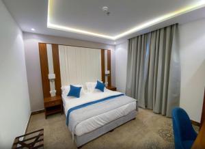 a bedroom with a large bed with blue pillows at نسناس للأجنحة الفندقية in Namirah