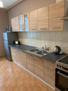 La cuisine est équipée de placards en bois, d'un évier et d'un réfrigérateur. dans l'établissement Apartament Iwona, à Mrągowo