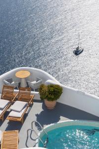 a boat with chairs and a swimming pool on the water at IKIES Santorini in Oia