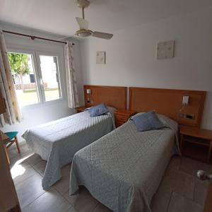 2 Betten in einem Zimmer mit Fenster in der Unterkunft Apartamento 2 habitaciones con piscina/aire acondicionado/Wi-Fi in Cala en Porter
