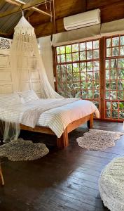 a bed with a net in a room with windows at LoerieRoep Estate - Mountainview Accommodation Nelspruit in Nelspruit