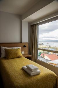um quarto com uma cama e uma grande janela em Gente del Sur - Cinco Hermanos em Ushuaia