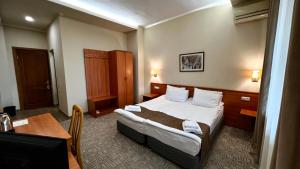 Habitación de hotel con cama y escritorio en Olympia Garden Hotel, en Ereván
