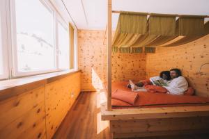 two people laying on a bed in a wooden room at Hotel Enzian - Adults Only in Obertauern