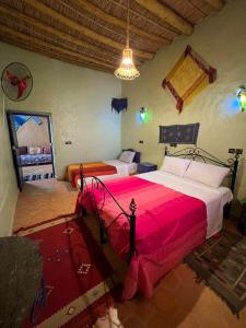 a bedroom with two beds with a red blanket at Merzouga Camp and Hostel in Merzouga