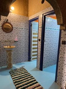 een badkamer met een deur naar een badkamer met een tapijt bij Merzouga Camp and Hostel in Merzouga