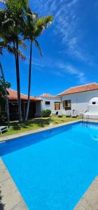 a swimming pool in front of a house with palm trees at Villa la Paz in Puerto de la Cruz