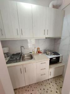 een kleine keuken met witte kasten en een wastafel bij Crystal Home near Airport in Artemida