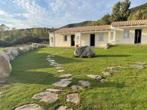 a house with a grassy yard with a stone path at Is Arenas Biancas Agriturismo in Teulada