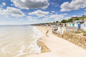 a beach with a row of houses and the ocean w obiekcie 6 Berth Caravan With Decking At Naze Marine Holiday Park Ref 17071p w mieście Walton-on-the-Naze