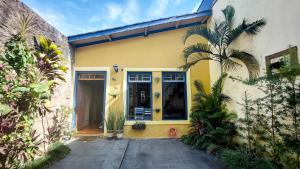 une maison jaune avec un palmier devant elle dans l'établissement Suítes em casa centenária no centro de Socorro, à Socorro