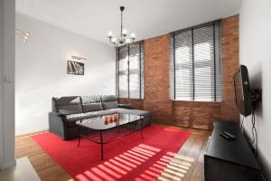 ein Wohnzimmer mit einem Sofa und einem roten Teppich in der Unterkunft Apartamenty Pomarańczarnia in Posen